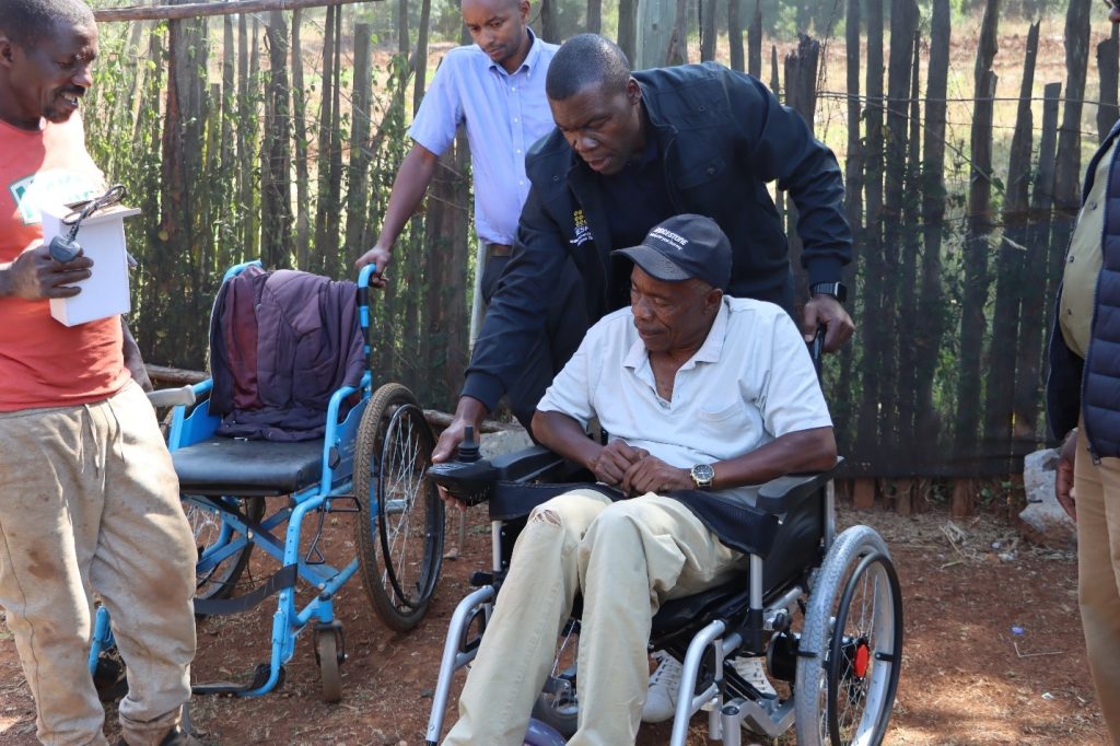 MESPT staff Akal, demonstrating how to use the motorized wheelchair to Ephantus